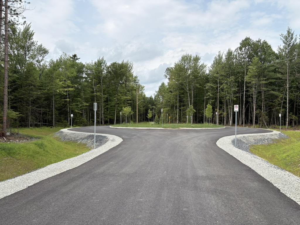 Rond-point asphalté entouré de forêt au Boisé du Golf